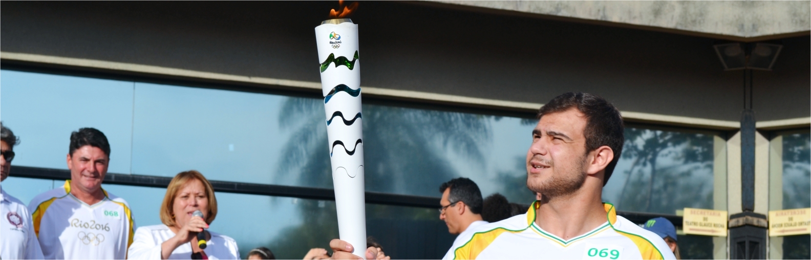 Imagem de um jovem segurando a tocha olímpica.