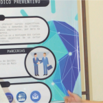 Duas pessoas na frente de um banner da feira.